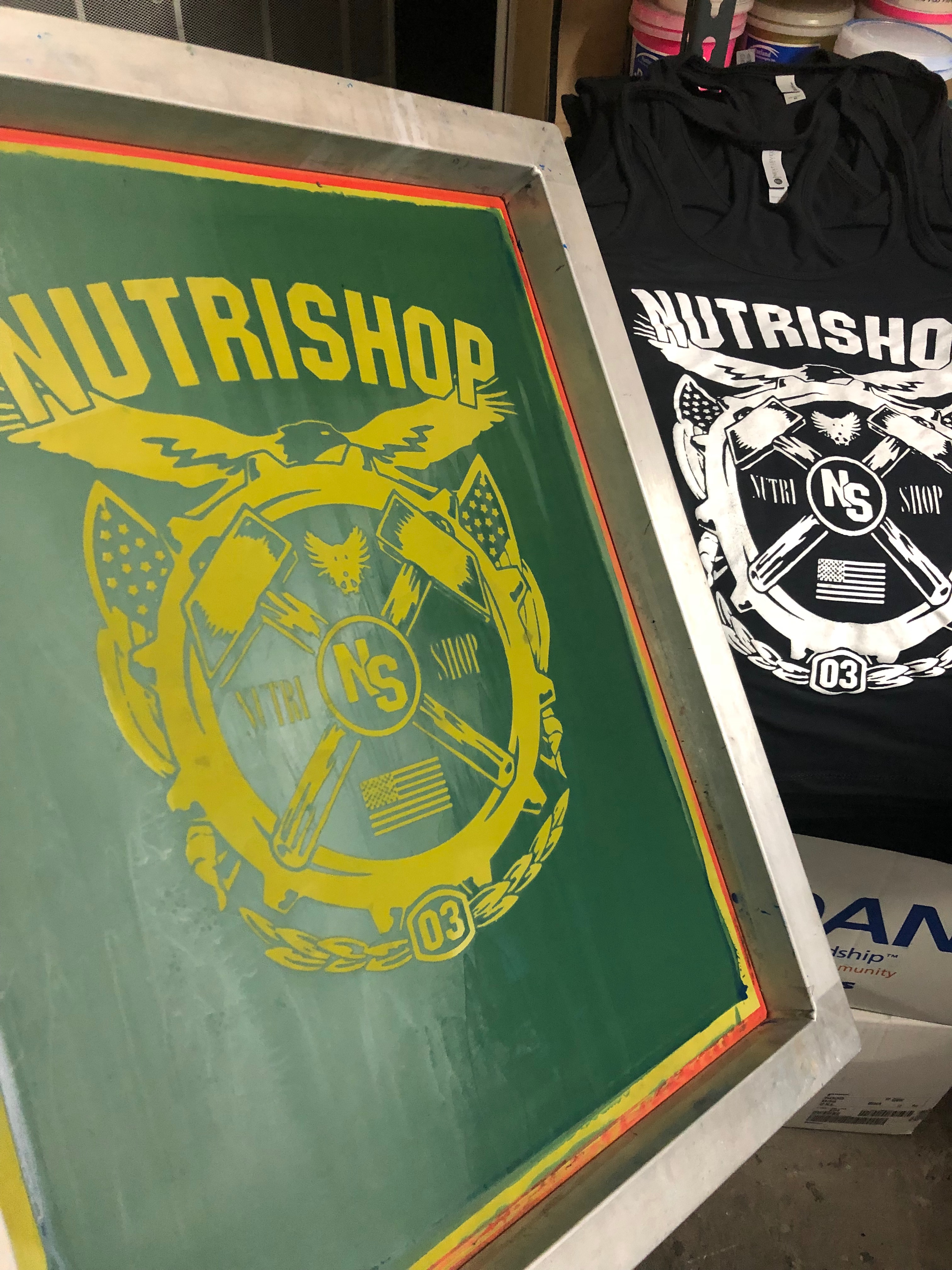 Nutrishop screens being printed on t-shirts.