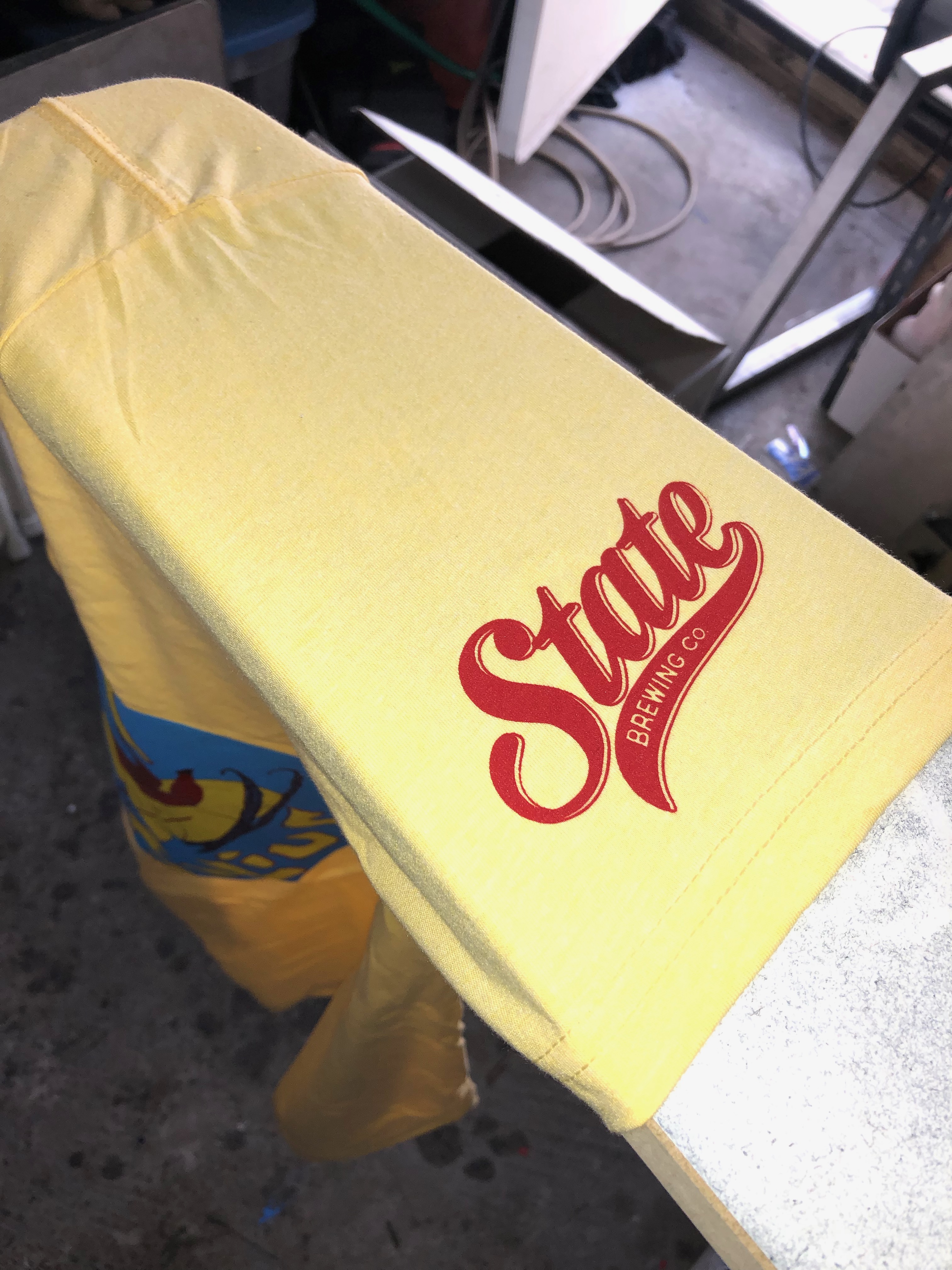 A State Brewing shirt sleeve printed with red ink.